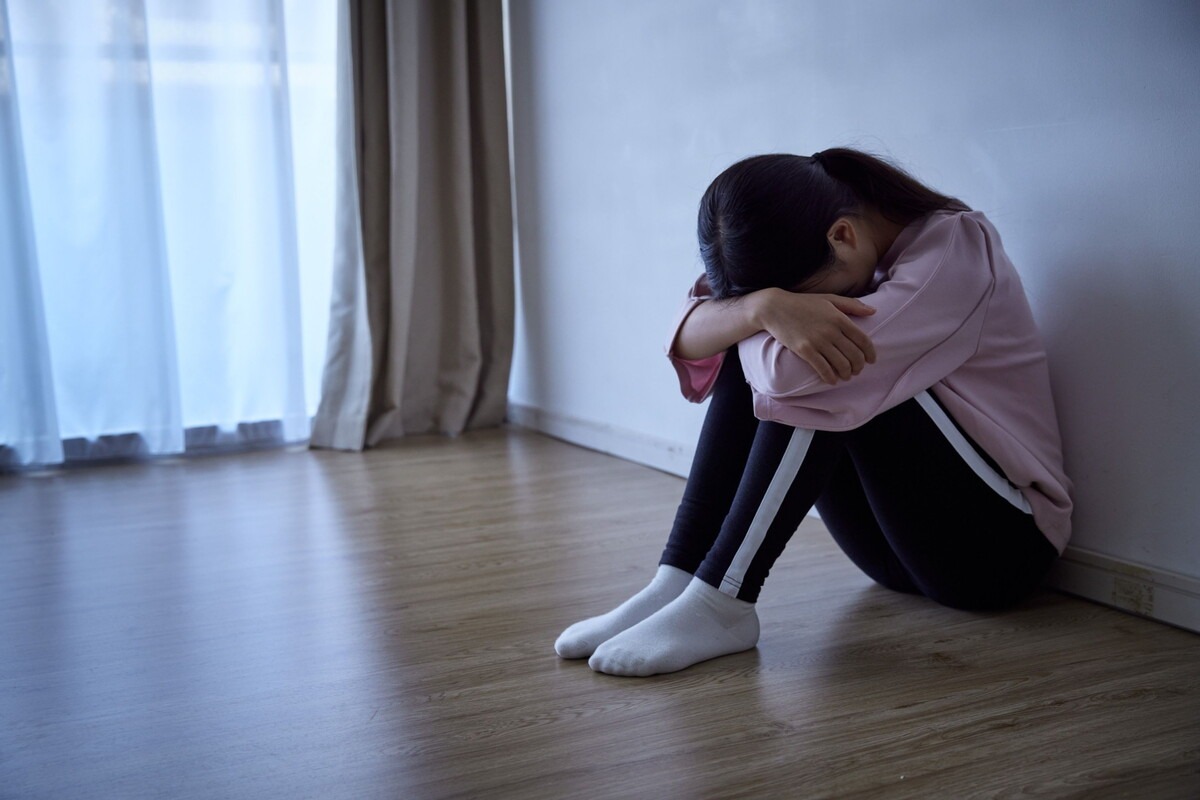 Verdrietig kind zit ineengedoken in een hoek van de kamer